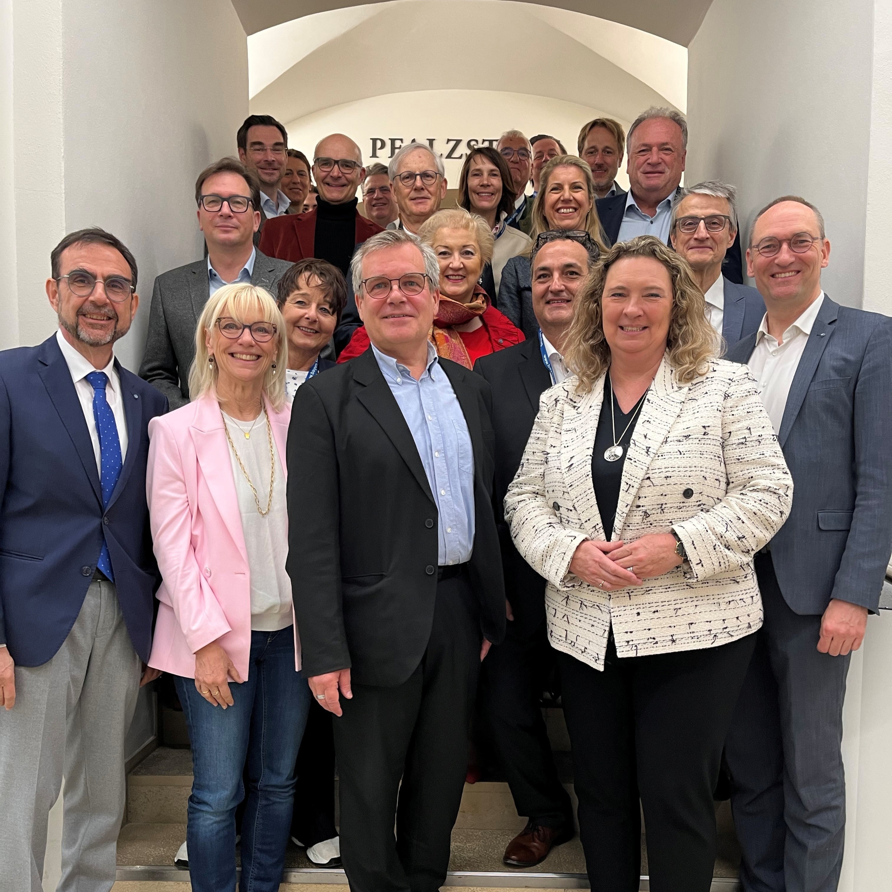 Eine Gruppe von Menschen steht auf einer Treppe und lächelt in die Kamera.